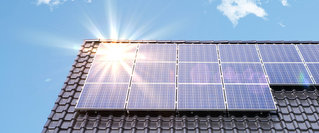 Solaranlage auf dem Dach eines Hauses im Sonnenlicht – Symbolbild für die Nutzung von Photovoltaik zur Senkung der Energiekosten inklusive staatlicher Fördermöglichkeiten für erneuerbare Energien.