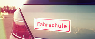 Heck eines Autos mit dem gut sichtbaren Schriftzug „Fahrschule“ – Symbolbild für den Führerschein und die steigenden Kosten sowie Finanzierungsmöglichkeiten der Fahrausbildung.
