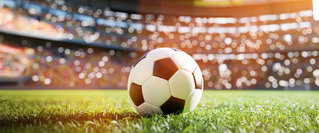 Fußball auf einem Spielfeld in einem beleuchteten Stadion – Symbolbild für den Profifußball sowie Prämien, Preisgelder und finanzielle Chancen bei sportlichen Erfolgen.