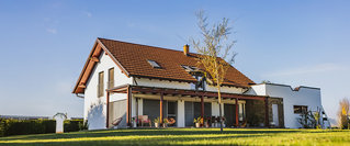 Modernes Einfamilienhaus mit Garten und Terrasse im Sonnenlicht.