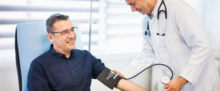 Ein Arzt misst bei einem Patienten den Blutdruck in der Praxis – medizinische Versorgung im Kontext von Reformen der gesetzlichen Krankenversicherung und deren Auswirkungen auf Leistungen und Beiträge.