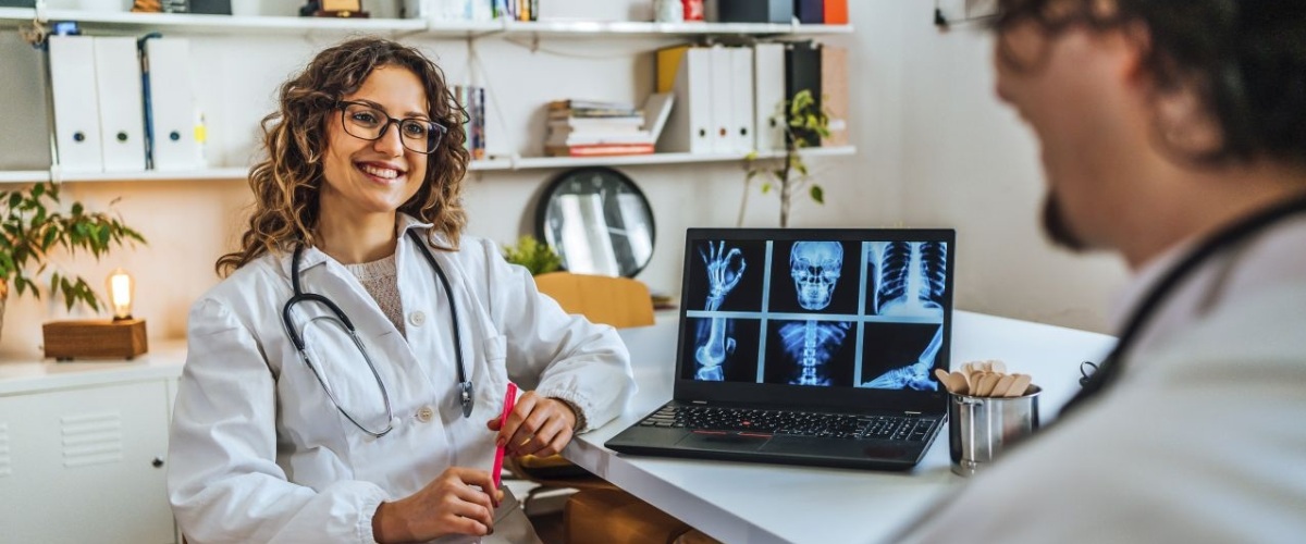 Two young cheerful doctors discussing diagnosis and examining the x-ray in clinic