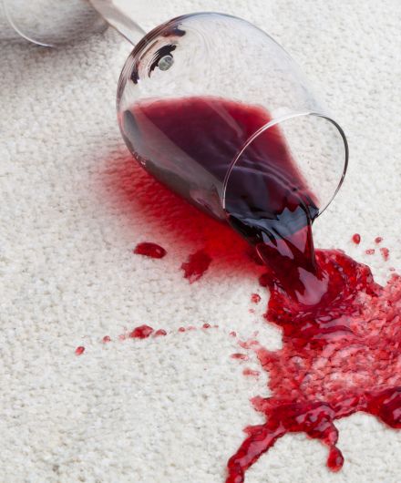 Umgefallenes Rotwein-Glas auf Teppich