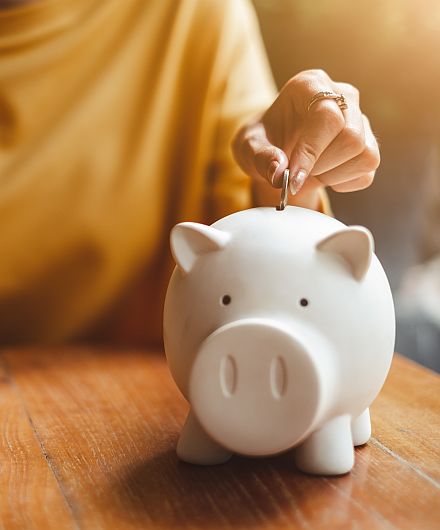 Sparschwein in das eine Münze geworfen wird 