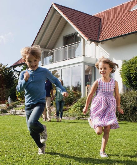 Zwei Kinder am Rennen im Garten vor einem Haus 